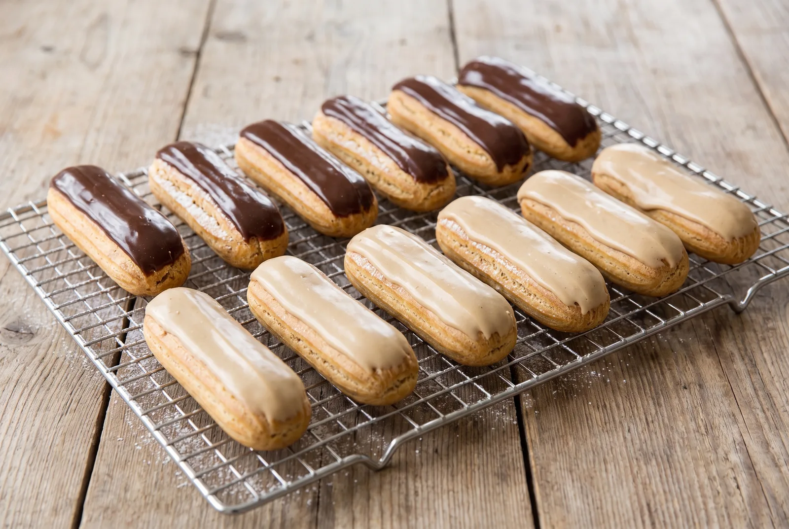 Row of finished éclairs topped with fondant and chocolate glaze